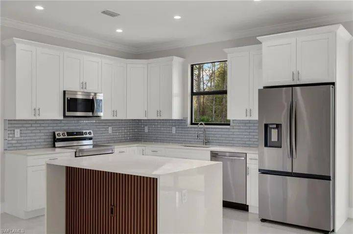 Kitchen featuring a center island, white cabinets, crown molding, sink, and appliances with stainless steel finishes