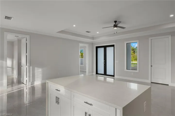 Kitchen with a center island, french doors, white cabinets, ceiling fan, and ornamental molding