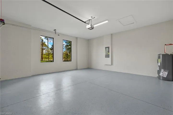 Garage featuring electric panel, electric water heater, and a garage door opener
