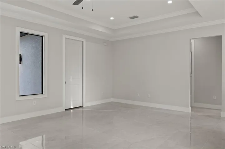 Empty room featuring a tray ceiling, ceiling fan, and ornamental molding