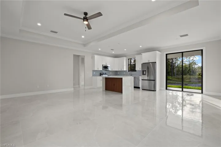 Kitchen with white cabinetry, stainless steel appliances, tasteful backsplash, a kitchen island, and ornamental molding