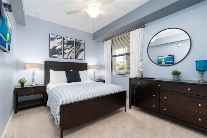 Wall-mounted television with built-in ceiling lighting, a window with blinds, and carpeting