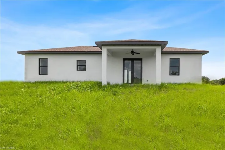 Rear view of house with ceiling fan, stucco siding, and a patio