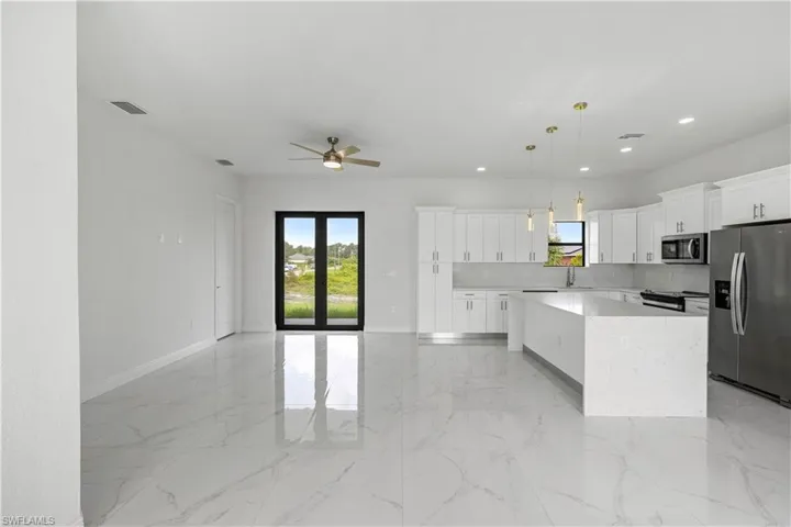 Kitchen featuring stainless steel appliances, tasteful backsplash, ceiling fan, decorative light fixtures, and white cabinets