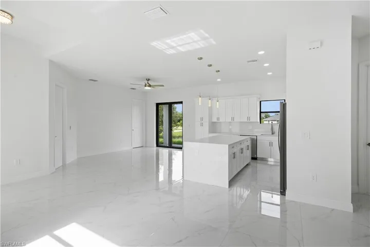 Kitchen featuring plenty of natural light, decorative light fixtures, white cabinetry, and open floor plan