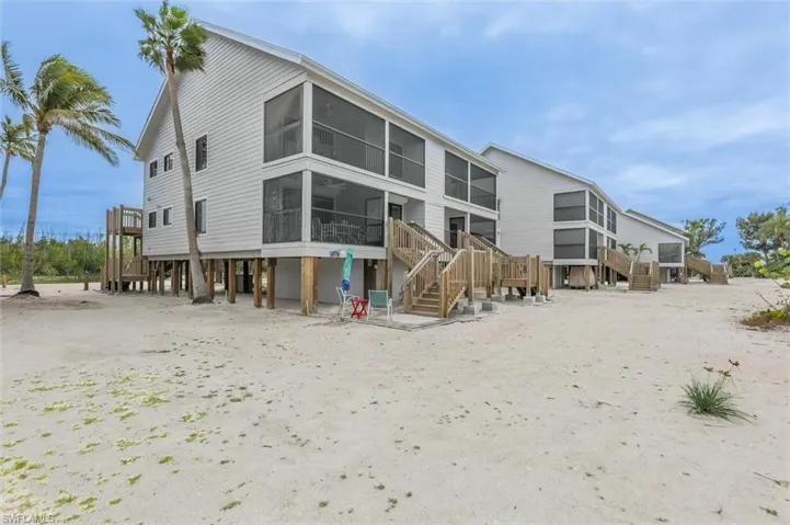Rear view of house featuring a sunroom, stairs, a deck, and a patio area