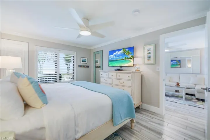Bedroom with wood tiled floors, ornamental molding, and a ceiling fan