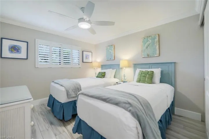 Bedroom featuring crown molding, wood finished floors, and a ceiling fan