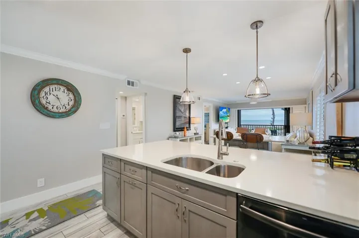 Kitchen with open floor plan, dishwasher, hanging light fixtures, crown molding, and wood tiled floors