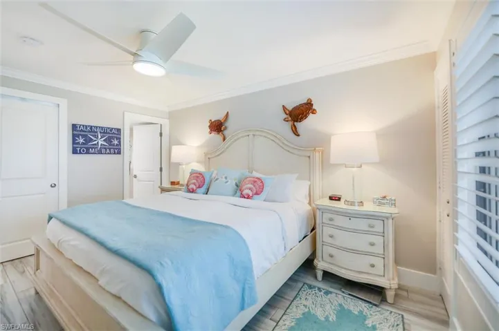 Bedroom with crown molding, wood finished floors, a closet, and ceiling fan