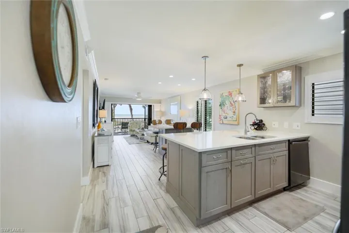 Kitchen featuring open floor plan, a breakfast bar area, glass insert cabinets, pendant lighting, and a peninsula