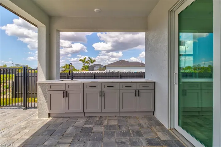 View of patio featuring area for grilling, a sink, and fence