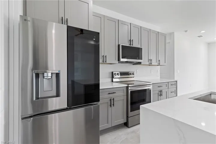 Kitchen with gray cabinets, recessed lighting, light stone countertops, visible vents, and stainless steel appliances