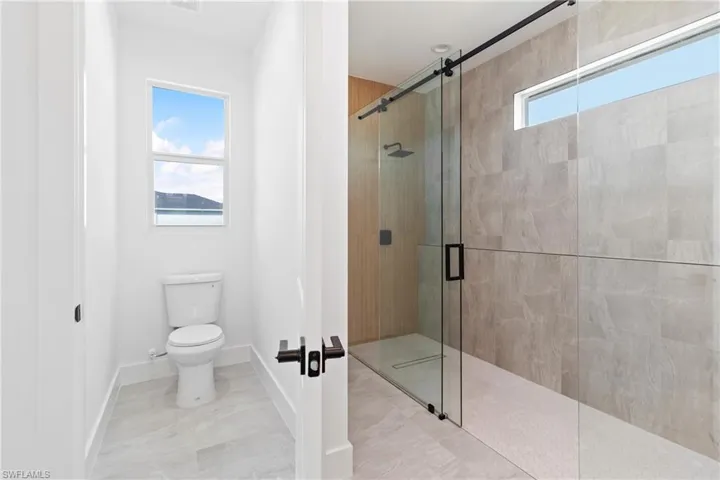 Full bath featuring toilet, a stall shower, and a wealth of natural light