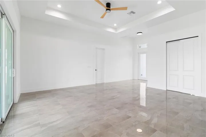 Unfurnished room featuring visible vents, baseboards, a raised ceiling, a ceiling fan, and recessed lighting