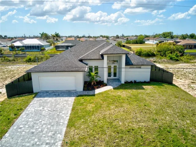 View of front of house with a garage, french doors, fence, and stucco siding