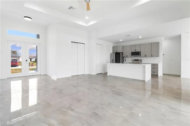 Unfurnished living room with a tray ceiling, baseboards, visible vents, and recessed lighting