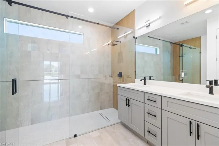 Full bathroom featuring a shower stall, double vanity, a sink, and visible vents