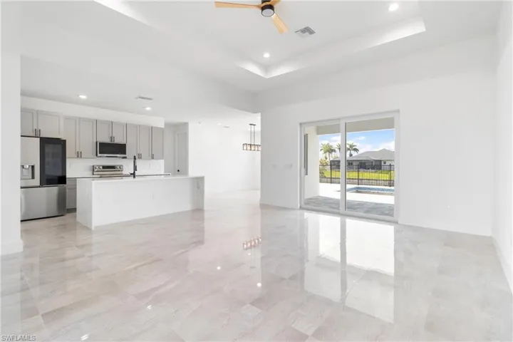 Unfurnished living room featuring visible vents, ceiling fan, a tray ceiling, and baseboards