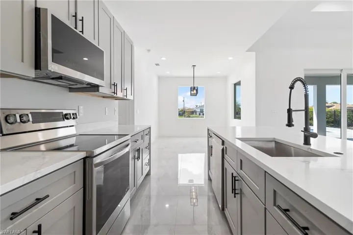 Kitchen featuring gray cabinets, a sink, plenty of natural light, and stainless steel appliances