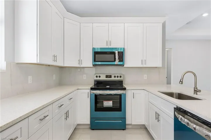 Kitchen featuring appliances with stainless steel finishes, sink, backsplash, and white cabinets