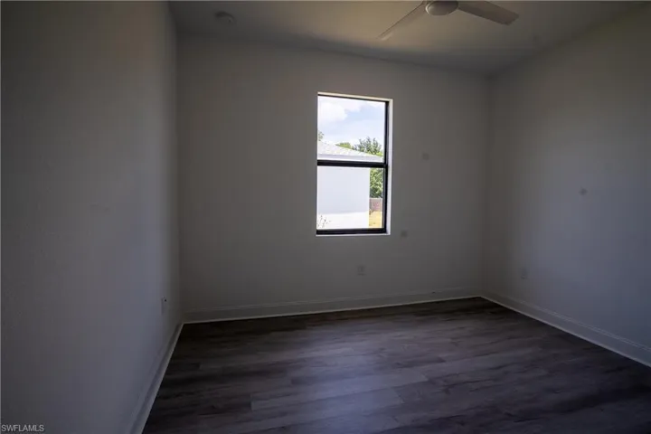 Room featuring wood-finish flooring, a contemporary window with black framing, and a ceiling fan