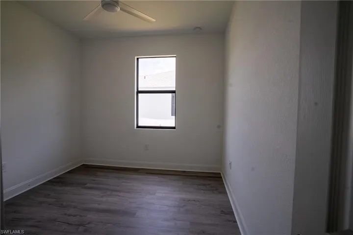 Room featuring wood-finish flooring, a contemporary ceiling fan, and a window with dark framing