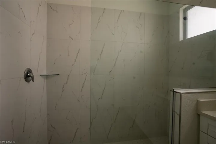 Spacious shower enclosure featuring large-format marble-look wall tiles