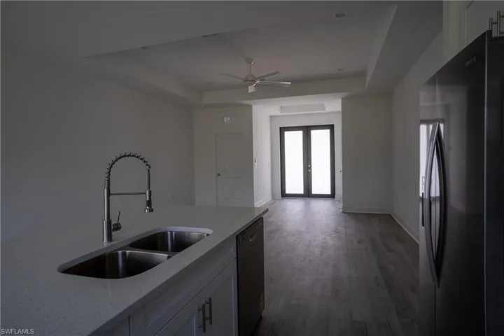 Kitchen island with an undermount double-basin stainless steel sink and a pull-down faucet, accompanied by a built-in dishwasher