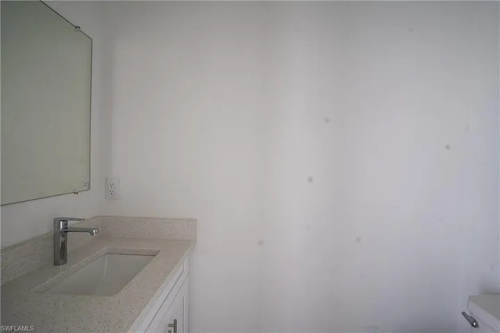 White vanity with an integrated rectangular sink, speckled countertop, and chrome faucet