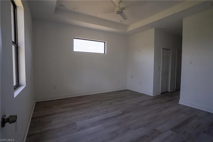 Spacious room featuring wood-finish flooring, a tray ceiling with a ceiling fan, and recessed lighting