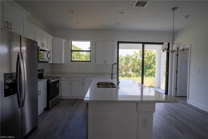 Kitchen featuring a central island with an undermount double basin sink and gooseneck faucet