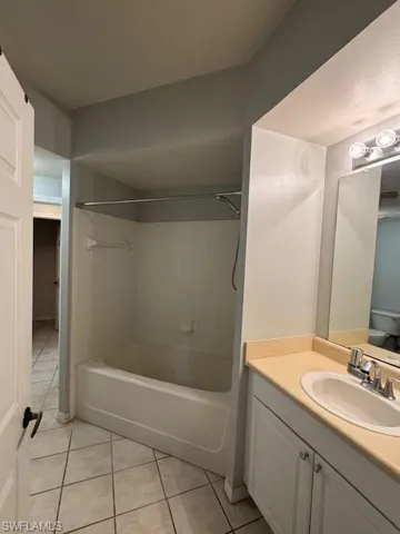Full bath with shower / bath combination, vanity, and light tile patterned flooring
