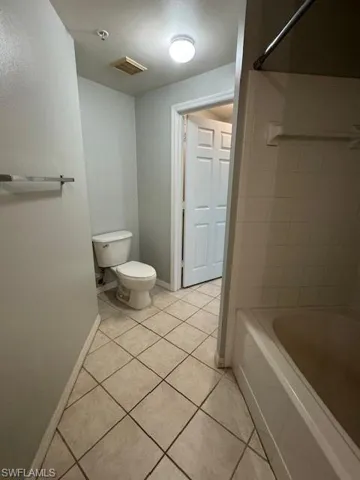 Bathroom with light tile patterned flooring, tub / shower combination, and a textured ceiling