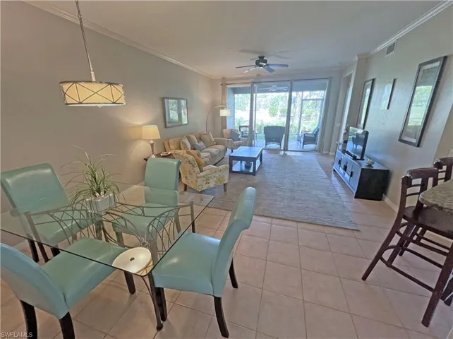 Dining and living room featuring ornamental molding, ceiling fan, and light tile flooring