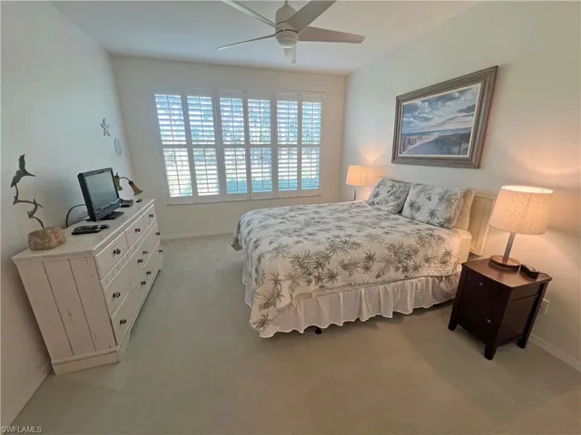 Bedroom with light carpet, ceiling fan, and baseboards