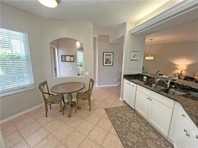 Kitchen with granite countertops, sink, white modern cabinets, crown lighting, and light tile floors