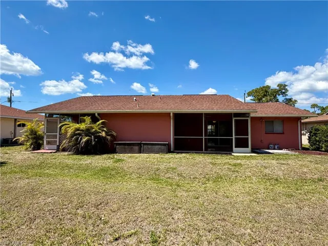 Back of house with a sunroom, a yard, and stucco siding
