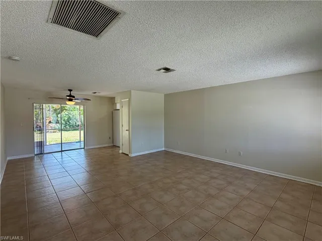 Spare room featuring a textured ceiling, ceiling fan, and light tile patterned floors