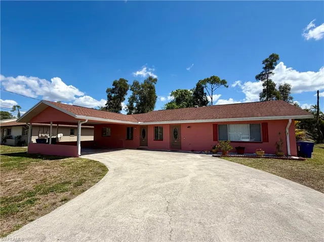 Ranch-style home with driveway, an attached carport, and a front yard