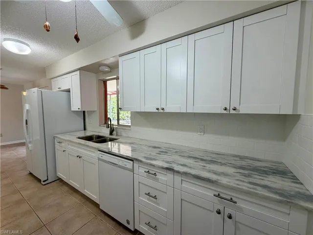 Kitchen featuring white cabinets, white appliances, a ceiling fan, a textured ceiling, and light stone countertops