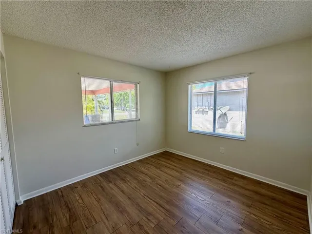 Unfurnished room featuring a textured ceiling and dark wood finished floors