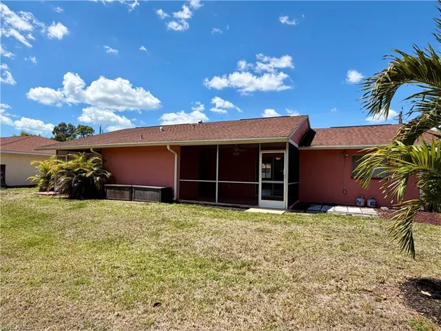 Rear view of house featuring a lawn, a sunroom, and stucco siding