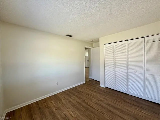Unfurnished bedroom with dark wood-type flooring, a textured ceiling, and a closet