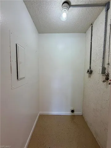 Laundry area with a textured ceiling and baseboards