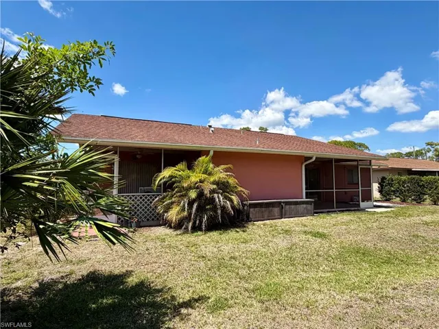 Back of house featuring a yard, stucco siding, and a sunroom