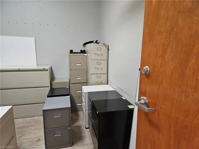 Unfurnished office with light wood-type flooring and a textured wall