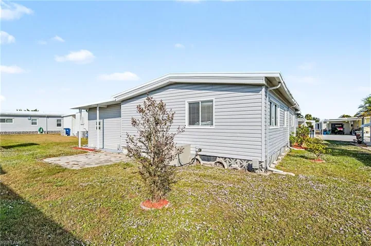 View of property exterior with a lawn and a patio