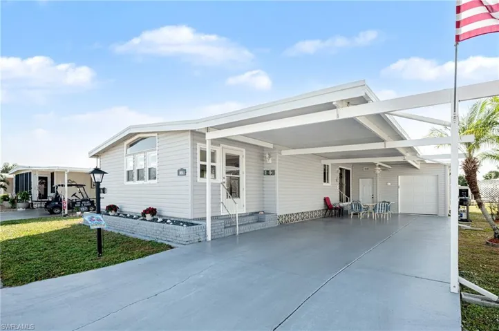 View of front facade featuring an attached carport, a patio, driveway, a front yard, and a garage