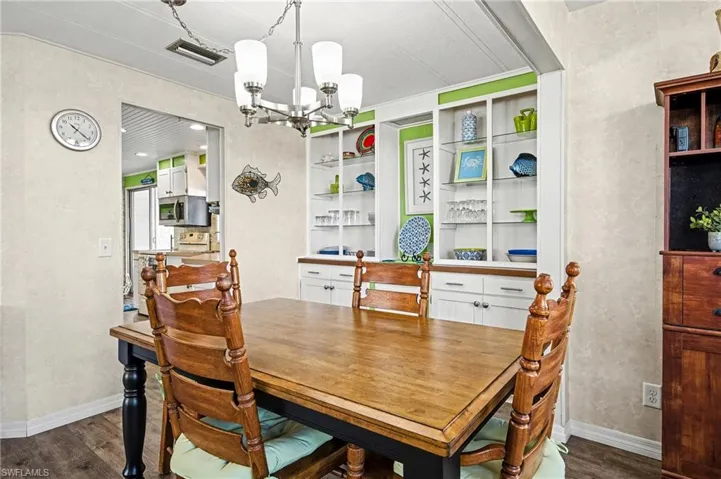 Dining area featuring a chandelier, dark wood-type flooring, a textured wall, and built in features